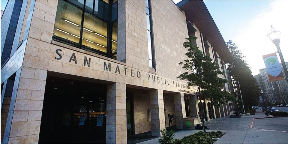 summer camps in the bay area: this is a photo of the outside of san mateo public library.  it looks like the sun is setting the building is stone.