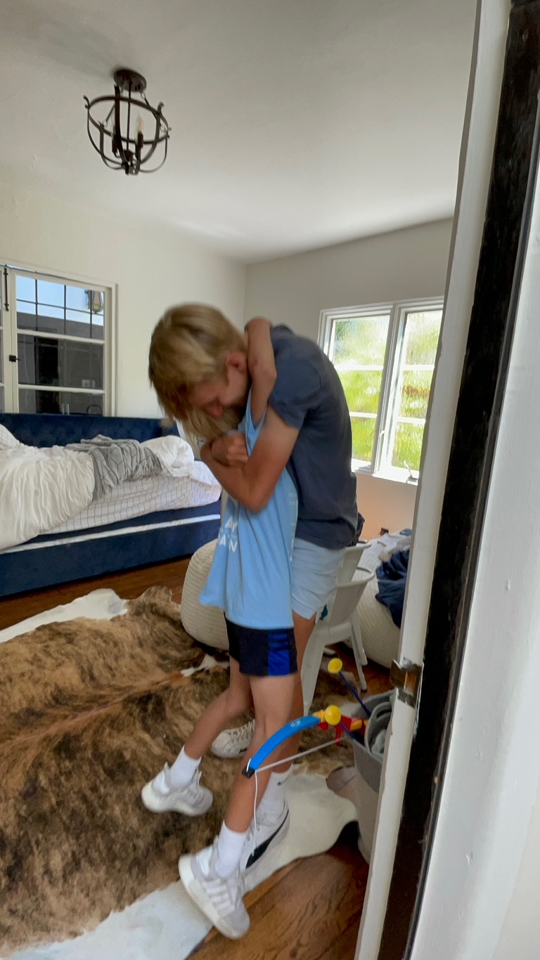 siblings hugging at home after a summer bike trek. kids are dressed casual