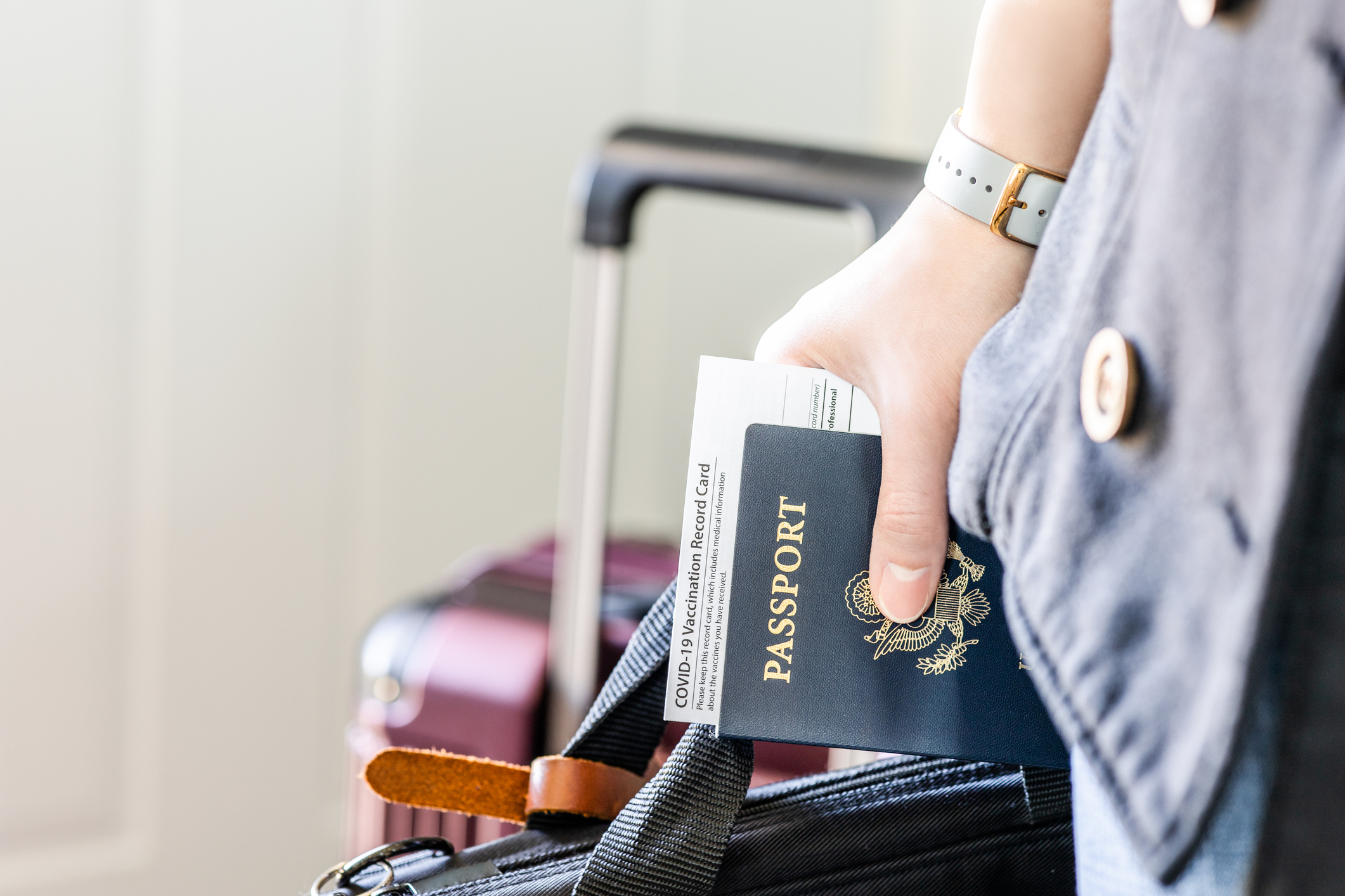 remote closing, woman is traveling with us passport and suitcase in the background.